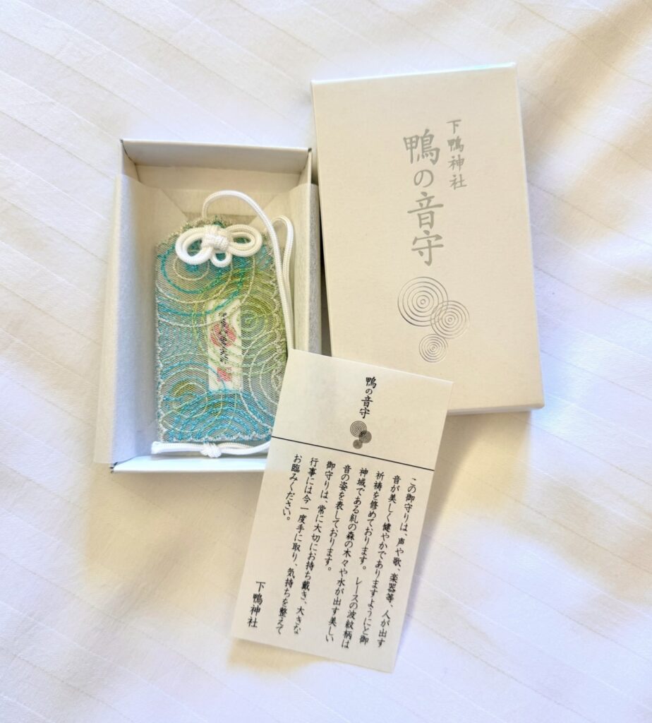 下鴨神社「鴨の音守」。糺の森の波紋柄をレースで表現した美しいお守り。箱と説明カード付き